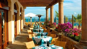 Un espace de restauration en plein air, avec des tables dressées pour les clients, offrant une vue panoramique sur l’océan.