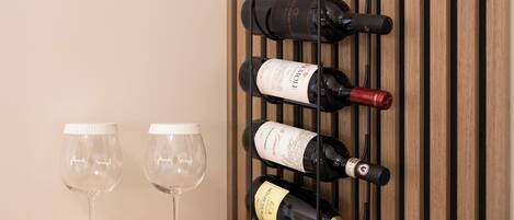 A wine rack with bottles and two empty wine glasses on a wooden surface.
