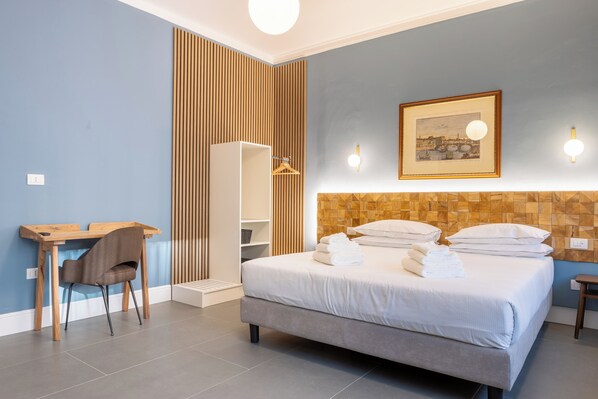 A hotel room with a bed, a desk, a chair, a wardrobe, and a framed picture on the wall. - Pier Capponi 17 Room & Suites (Florence)