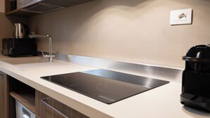 Cocina moderna con cocina por inducción negra, cafetera y hervidor en la encimera.