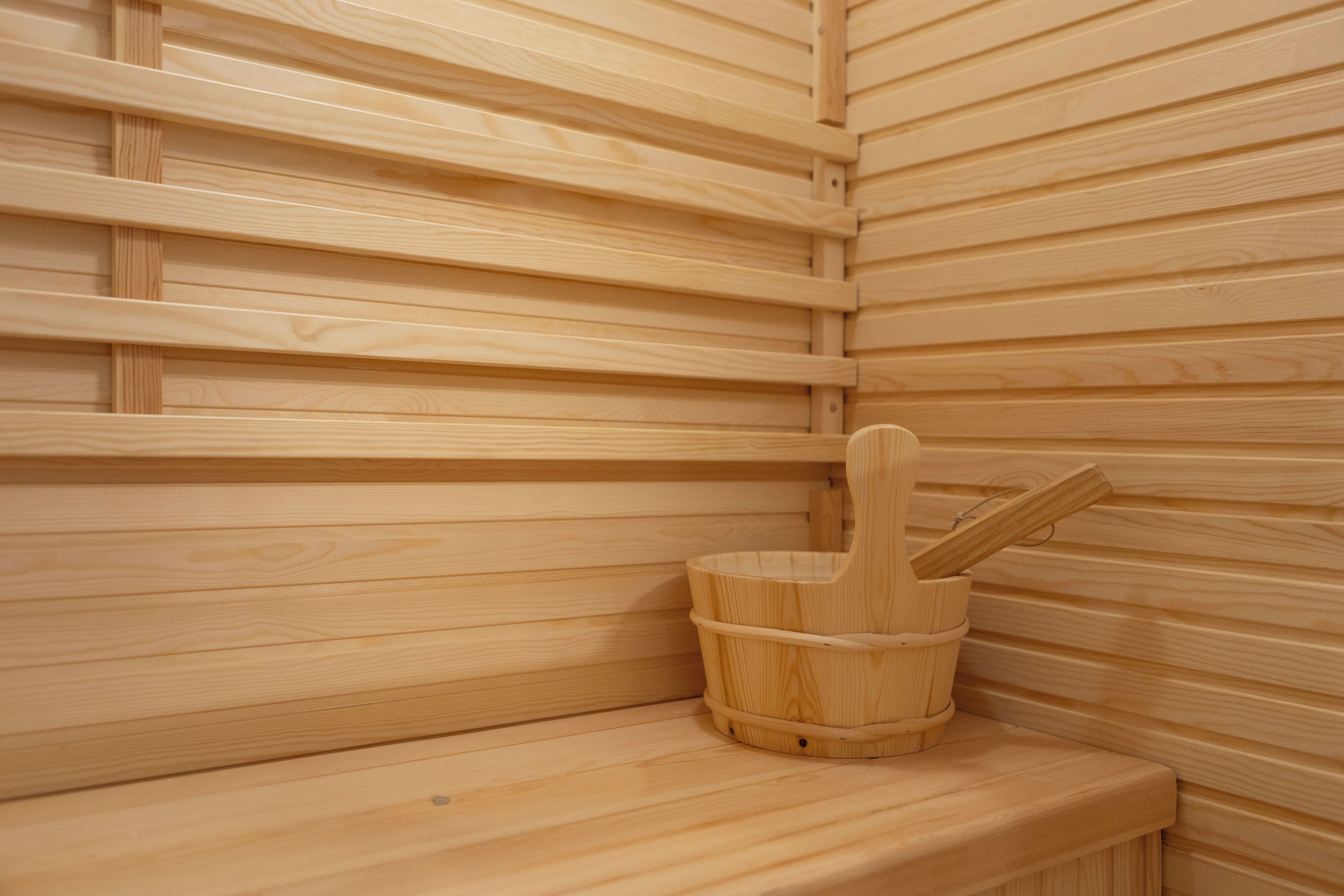 A wooden sauna with benches and a wooden bucket.