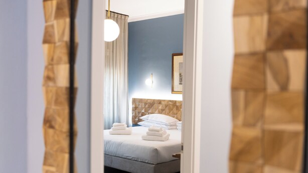 Una habitación de hotel con una cama, una mesita de noche, un reloj de pared y un cuadro en la pared.