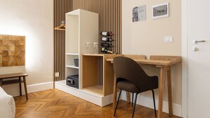 Habitación compacta con escritorio de madera, una silla, armario con espacio para colgar y una pequeña estantería.