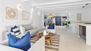 Ein modernes Wohnzimmer mit einer Couch, einem Couchtisch und einem Essbereich mit Stühlen.