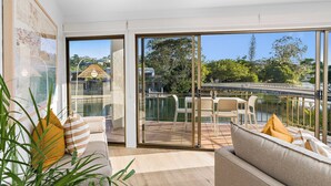 Un salon moderne doté d’une grande porte-fenêtre coulissante donnant sur un balcon avec vue sur un pont et la verdure environnante.