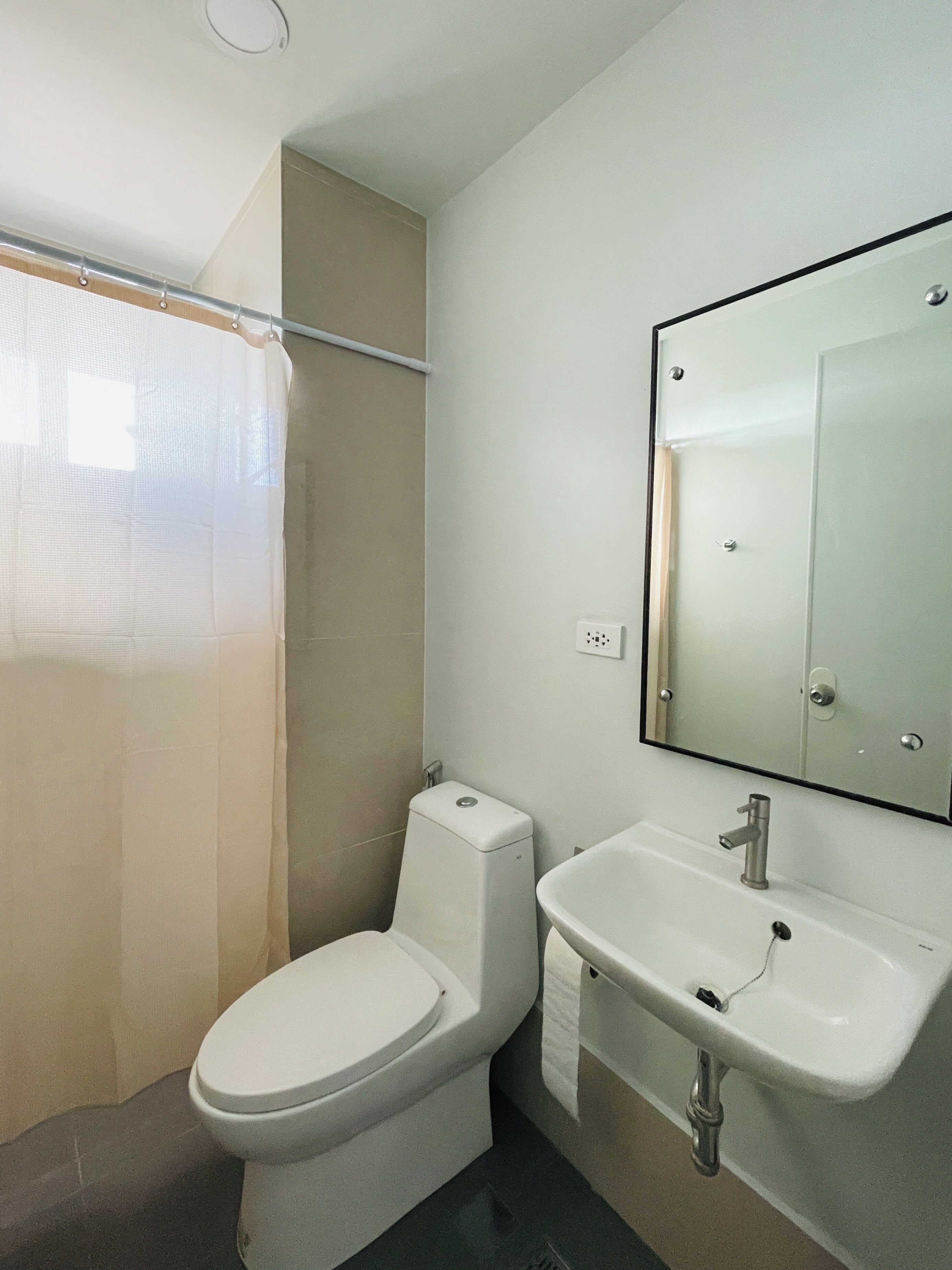 A modern bathroom with a toilet, sink, and mirror.
