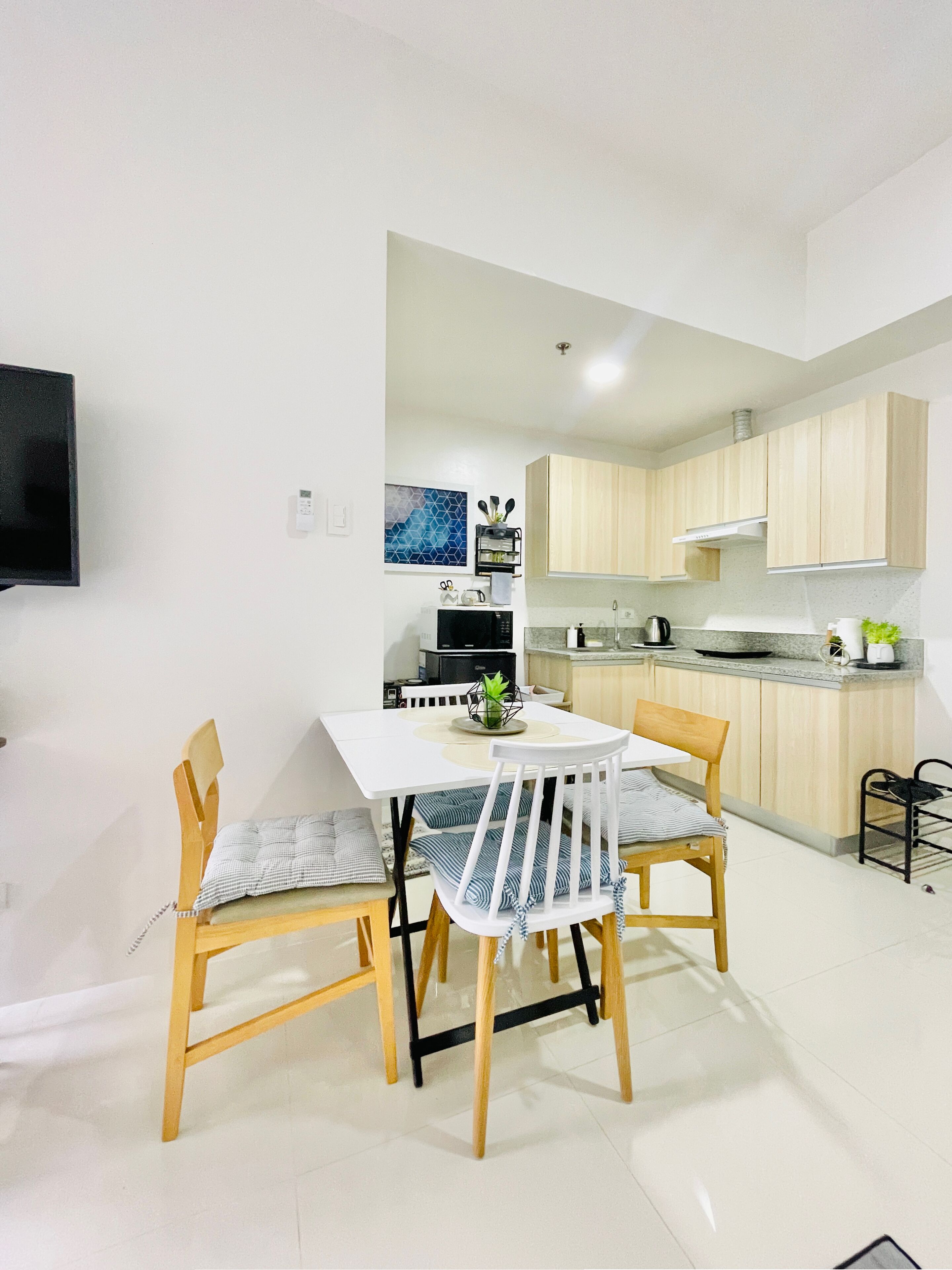 Una cocina moderna con armarios de madera, encimera blanca y comedor con mesa y sillas de madera.