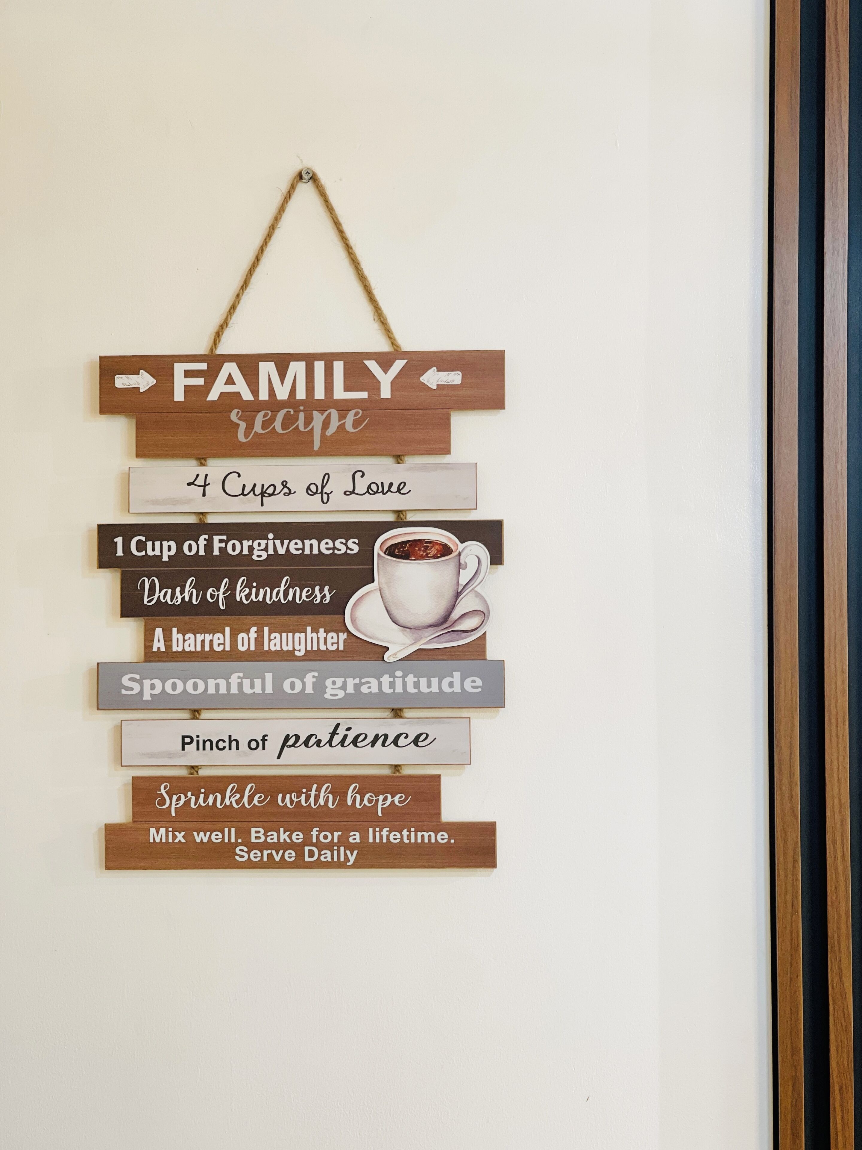A wall hanging with a family recipe theme, including phrases like "4 Cups of Love" and "1 Cup of Forgiveness."