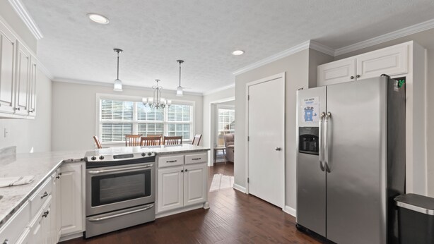 A modern kitchen with white cabinetry, stainless steel appliances, and a wooden floor.
