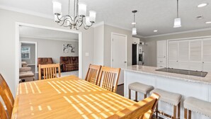A spacious kitchen with a central island, wooden dining table, and chairs.