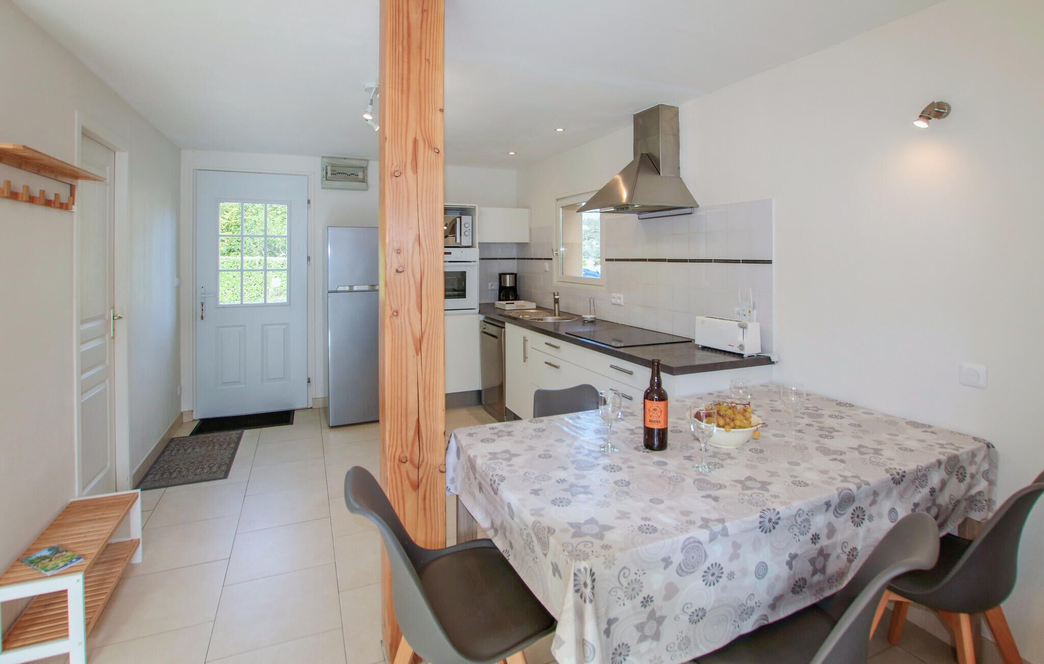A compact kitchen with a dining area, featuring a refrigerator, oven, and a wooden column.