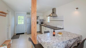 A compact kitchen with a dining area, featuring a refrigerator, oven, and a wooden column.