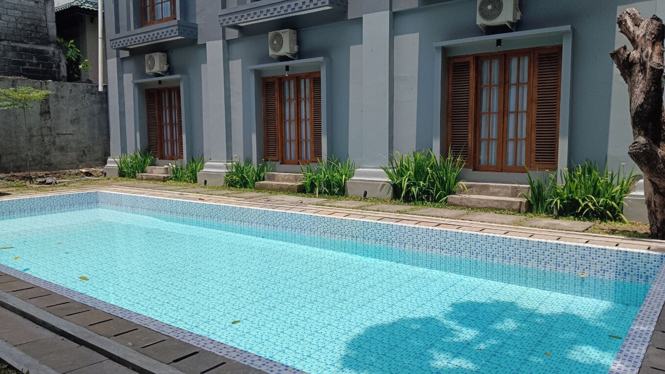 A rectangular swimming pool with a tiled edge, surrounded by a concrete deck.