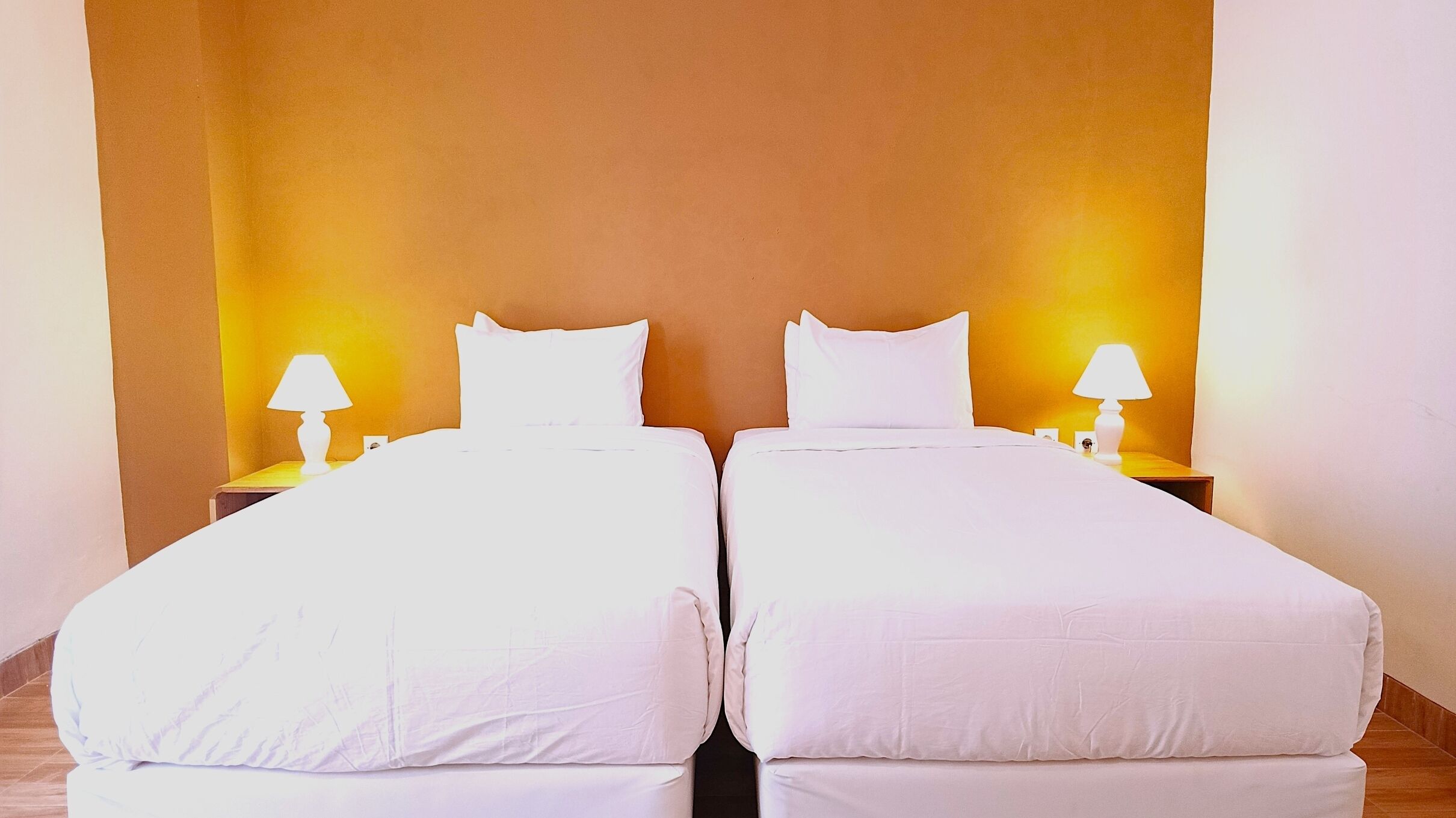 Une chambre double avec deux lits, chacun étant équipé d’une table de chevet et d’une lampe.