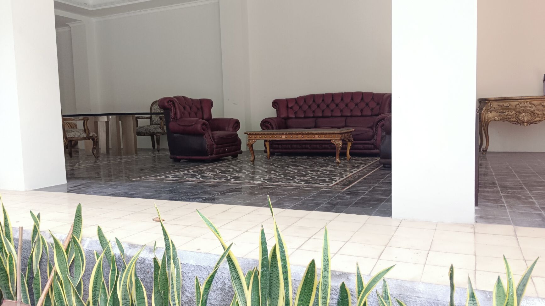 A lobby with a marble floor, two purple sofas, a coffee table, and a patterned rug.