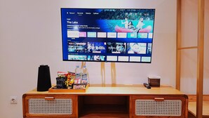 Een televisie bevestigd aan een houten standaard, met een dienblad waarop hapjes en een fles staan.