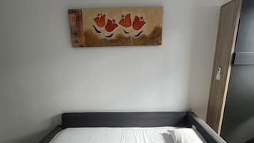 Een hotelkamer met een bed, een schilderij en een airconditioning.