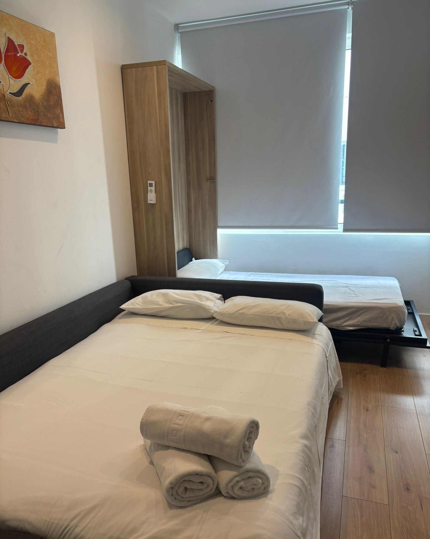A hotel room with two beds, a wardrobe, and a window.