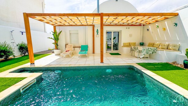 A swimming pool with a wooden pergola, a sunbed, and a seating area with cushions. - Dar Nour Charme et Tranquilit Hammamet (Hammamet)