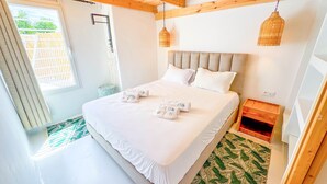 A bedroom with a wooden ceiling, a bed with white linens, two hanging wicker lamps, and a green patterned rug. - Dar Nour Charme et Tranquilit Hammamet (Hammamet)