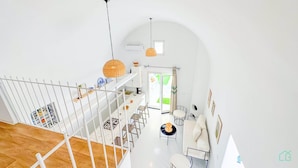 A spacious, well-lit interior with a high ceiling, a staircase, a dining area, and a view of the outdoors. - Dar Nour Charme et Tranquilit Hammamet (Hammamet)