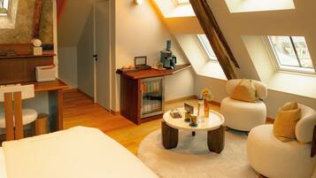 A cozy loft bedroom with a skylight, a wooden desk, a comfortable sofa, and a small round table.