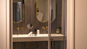 A modern bathroom with two oval mirrors, a white sink, and a towel rack.
