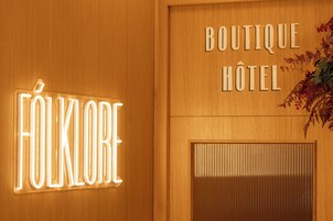 Una pared de madera con letreros iluminados que dicen "FOLKLORE" y "BOUTIQUE HOTEL".