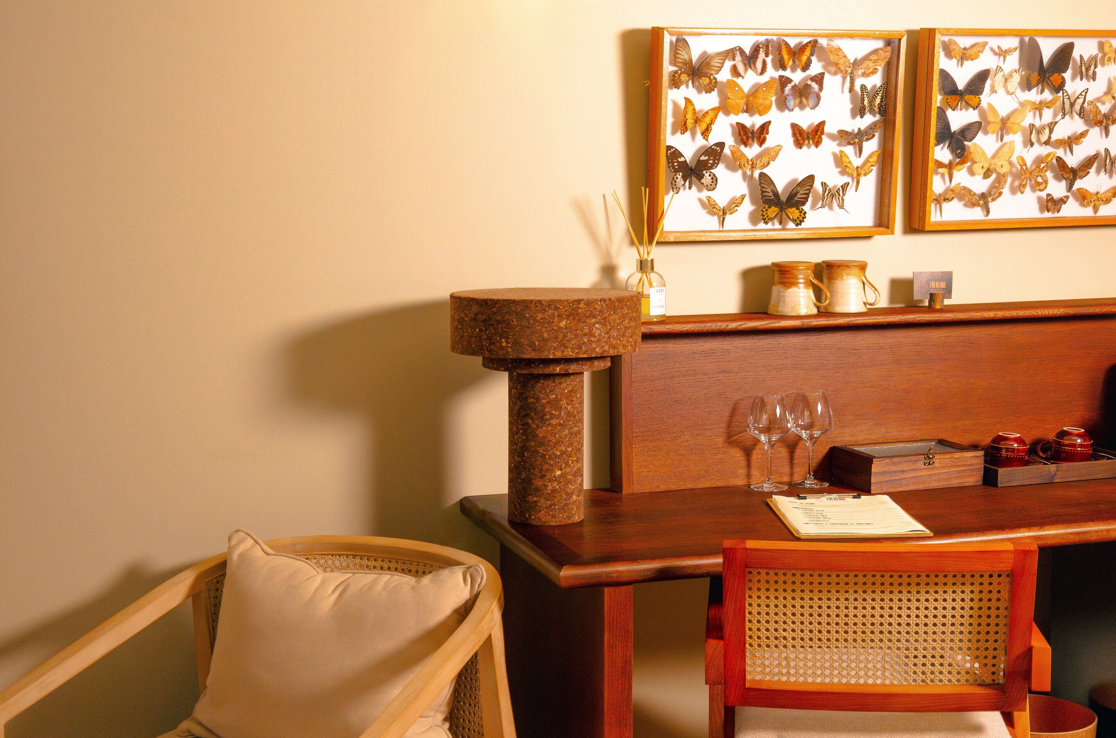 A dining area with a wooden table, chairs, a decorative lamp, and framed butterfly artwork on the wall.