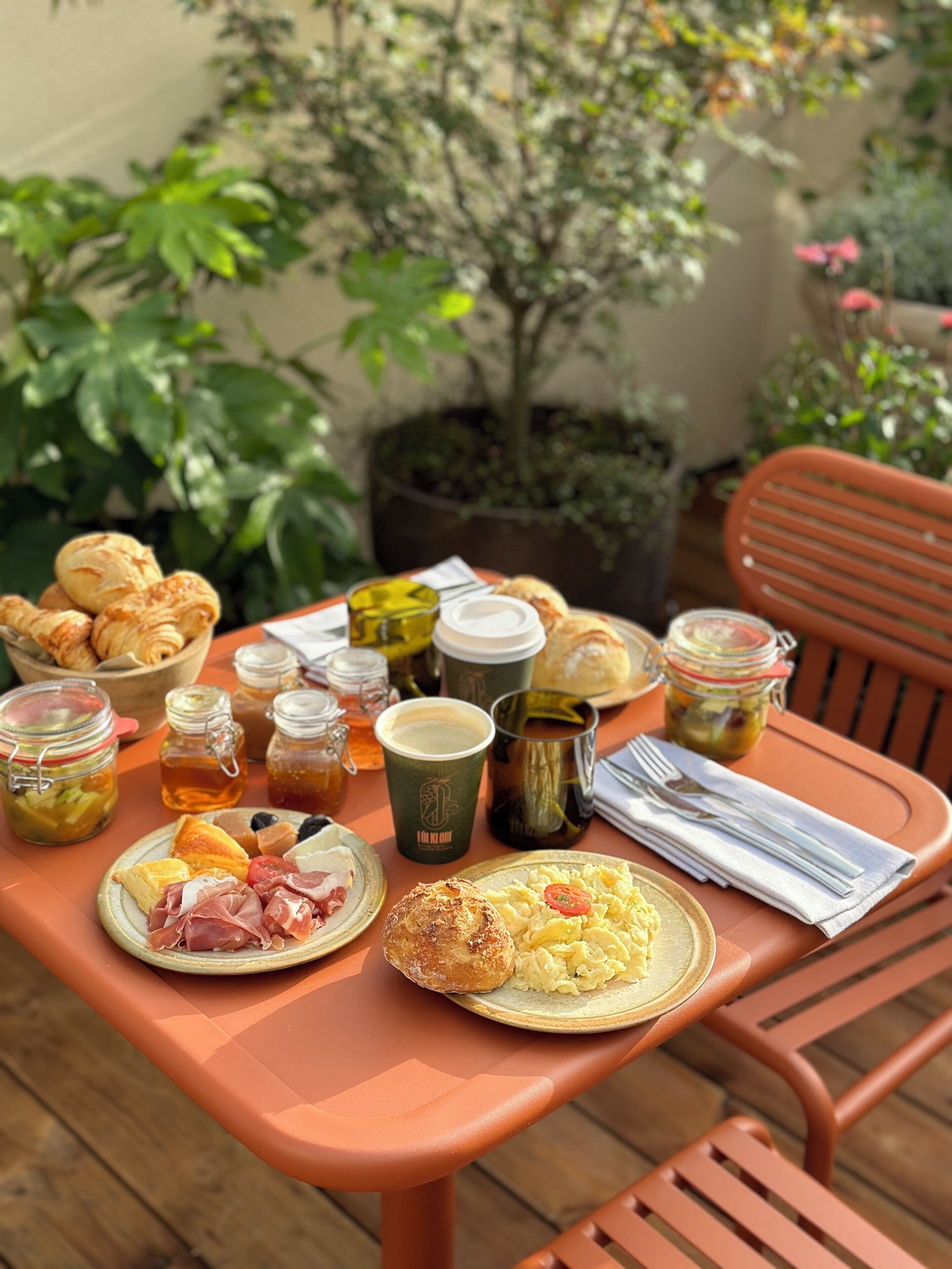 Una mesa servida con diferentes alimentos y bebidas, incluyendo pasteles, un plato de huevos y una taza de café.