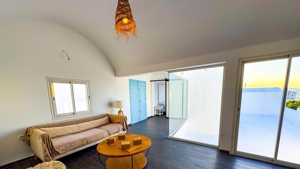 A spacious room with a curved ceiling, a sofa, a round wooden table, and a fur ottoman. - Padel Resort 1bd Apartment (Raf Raf)