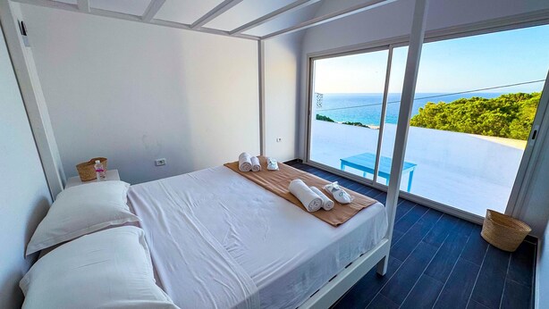 Une chambre à coucher moderne avec un grand lit, une table de chevet en bois et une vue sur la mer.