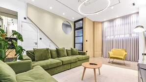 A modern living room with a green sectional sofa, a round coffee table, and a yellow armchair. - Luxury Abode: 5-Bed Haven Ideal for Big Groups! (London)