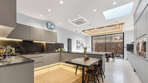 A modern kitchen with a central island, recessed lighting, and a skylight. - Luxury Abode: 5-Bed Haven Ideal for Big Groups! (London)