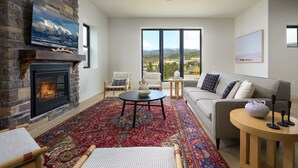 Una sala de estar con chimenea, un sofá, una mesa de centro y vistas a la montaña.