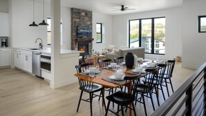 Una cocina amplia con electrodomésticos modernos, una zona de comedor con una mesa grande preparada para seis personas y una chimenea.