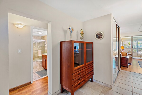 A hallway with a wooden cabinet, a door leading to a bathroom, and a view into a dining area.