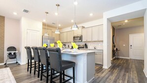 A modern kitchen with a central island, bar stools, pendant lighting, and a herringbone wood floor. - Family Friendly 5Bd Near Disney @ Windsor Cay 1269 (Clermont)
