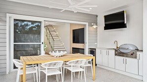 A modern kitchen with a built-in grill, white cabinetry, and a large window overlooking a deck. - Dog friendly Paradise, 1-2B Bagnall Ave - water views, air con, Wi-Fi (Salamander Bay)