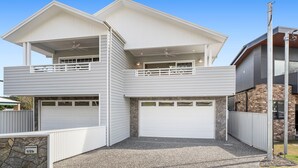 A two-story house with a garage, a balcony, and a stone foundation. - Dog friendly Paradise, 1-2B Bagnall Ave - water views, air con, Wi-Fi (Salamander Bay)