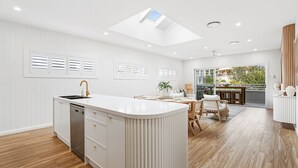 A modern kitchen with a central island, white cabinetry, and a skylight. - Dog friendly Paradise, 1-2B Bagnall Ave - water views, air con, Wi-Fi (Salamander Bay)
