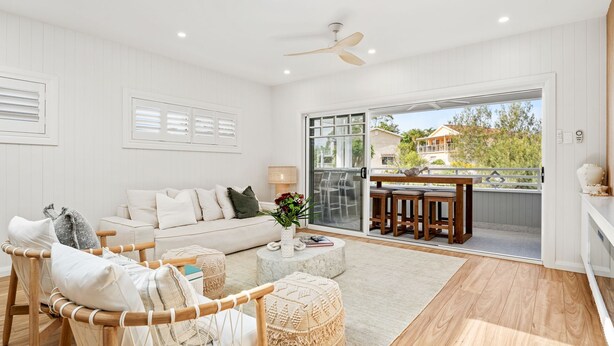 A spacious living room with a white sofa, a wooden chair, and a dining area with a table and chairs. - Dog friendly Paradise, 1-2B Bagnall Ave - water views, air con, Wi-Fi (Salamander Bay)