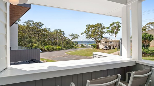 A balcony with a view of a residential street, a car parked in the driveway, and a house in the background. - Dog friendly Paradise, 1-2B Bagnall Ave - water views, air con, Wi-Fi (Salamander Bay)