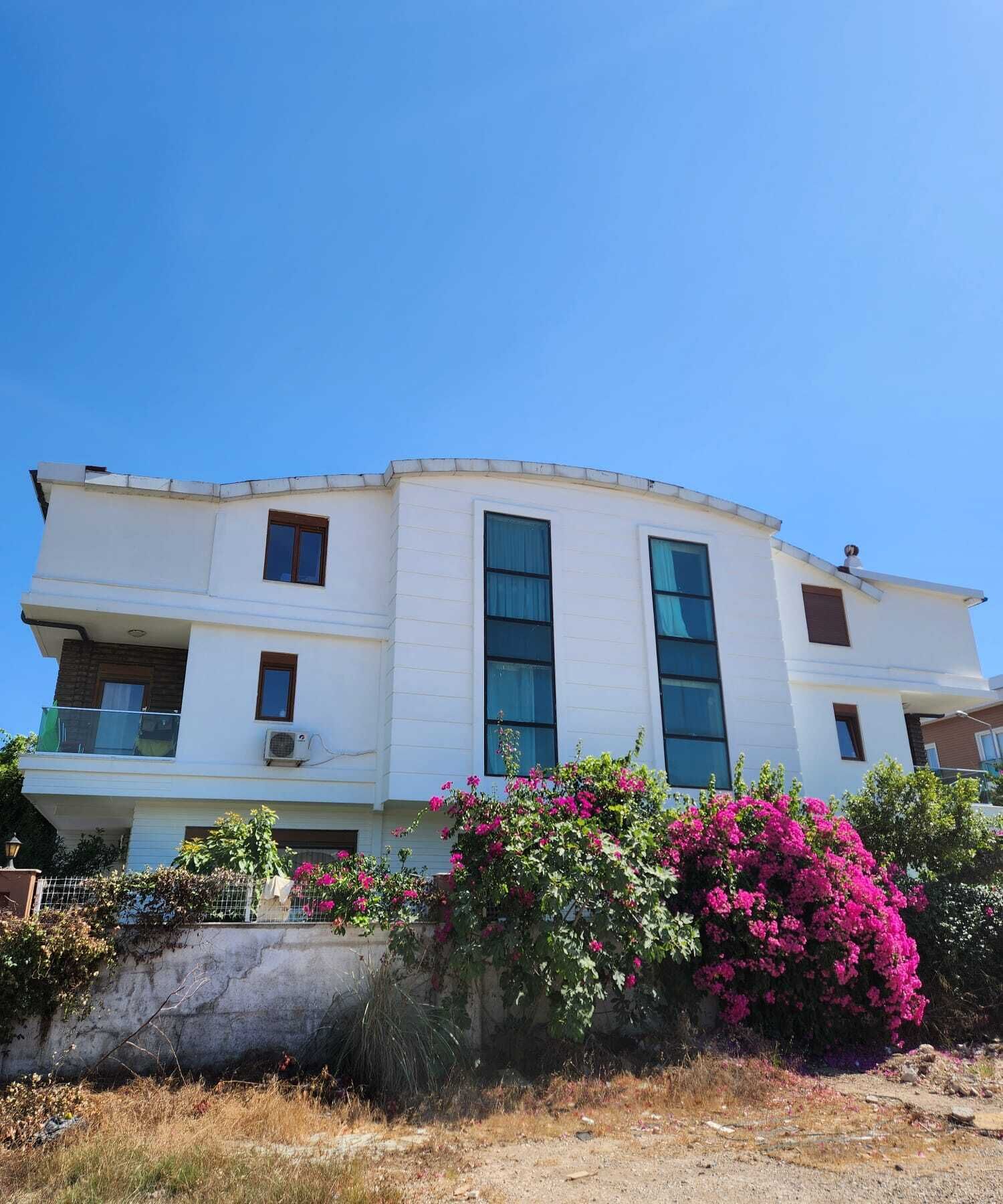 A two-story building with a flat roof, large windows, and a balcony.