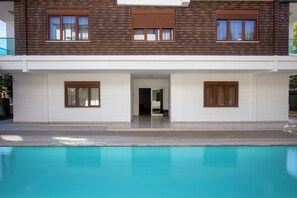 Una casa de dos pisos con una piscina al frente.