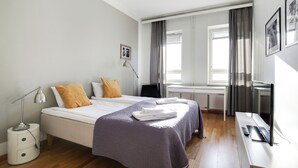 A modern hotel room with a neatly made bed, a desk with a computer, and a window with curtains.