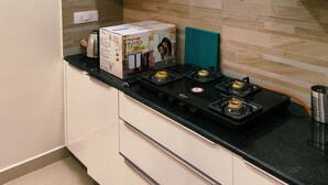 Una cucina moderna con mobili bianchi, un piano di lavoro nero e un fornello a gas.