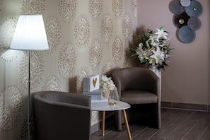 A modern room with a brown leather armchair, a small round table, a lamp, and a decorative wall piece. - Árnyas Panzió Gödöllő (Gödöllő)
