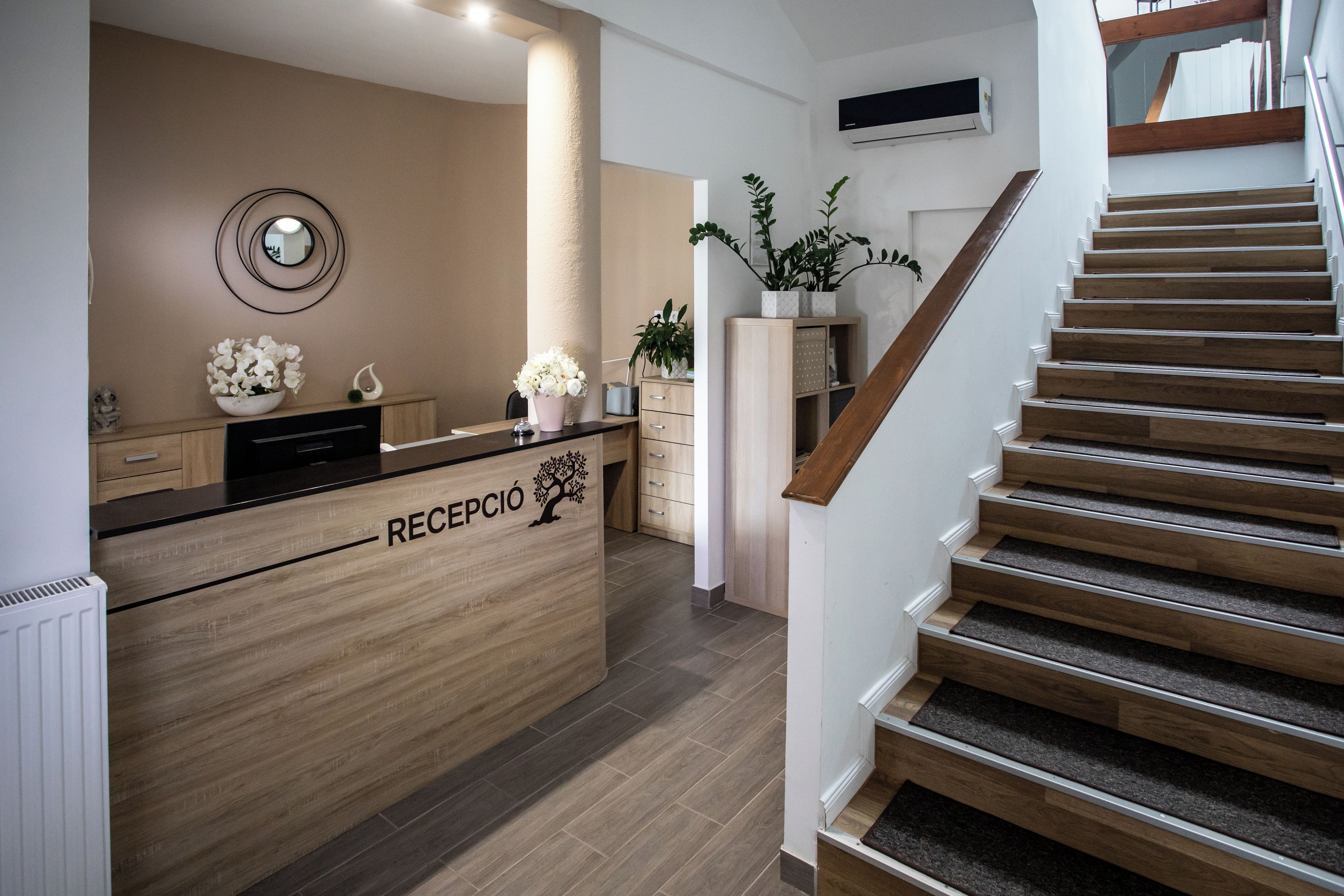 A reception area with a wooden counter, a mirror, and a staircase.