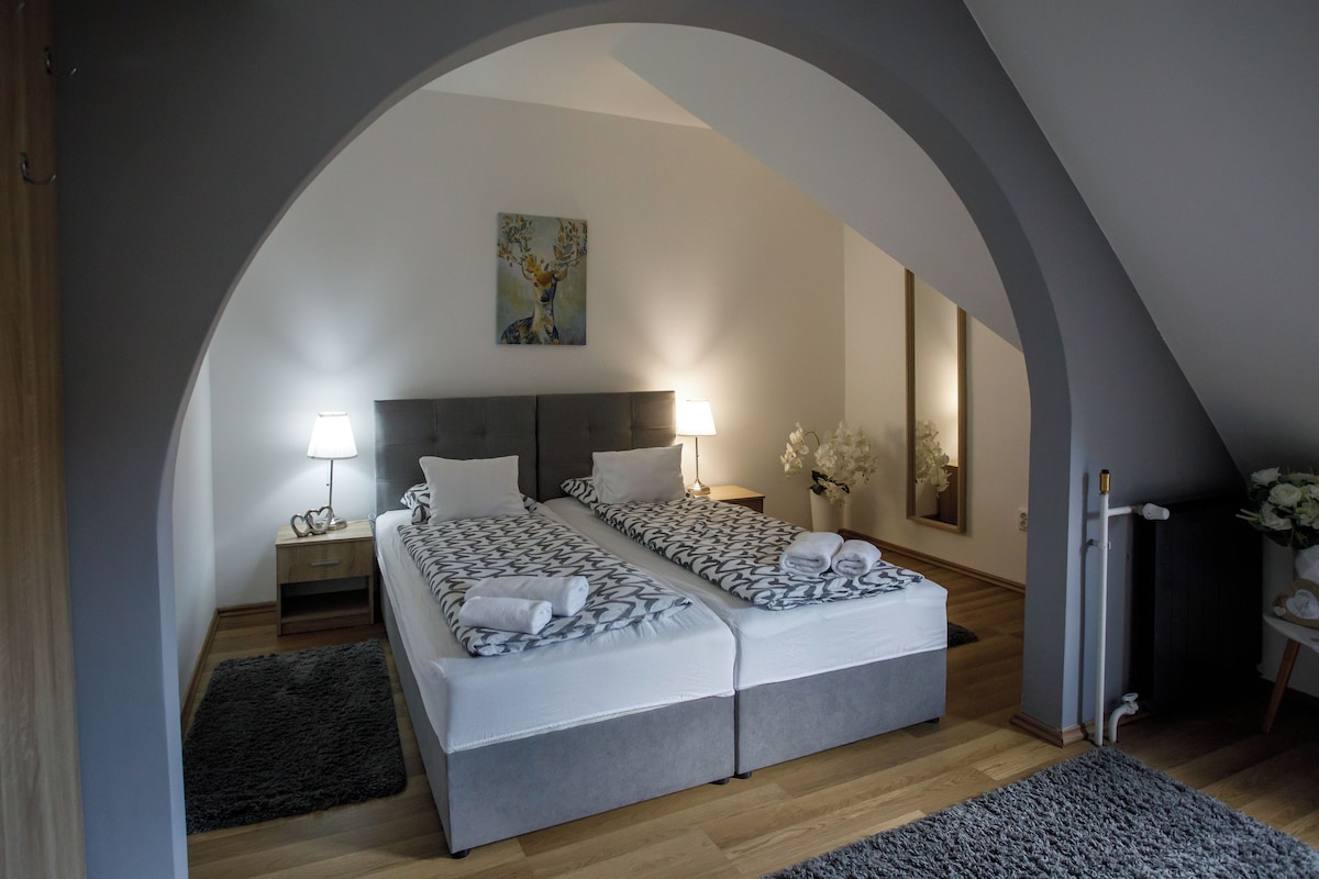 A bedroom with two beds, a painting on the wall, and a mirror.